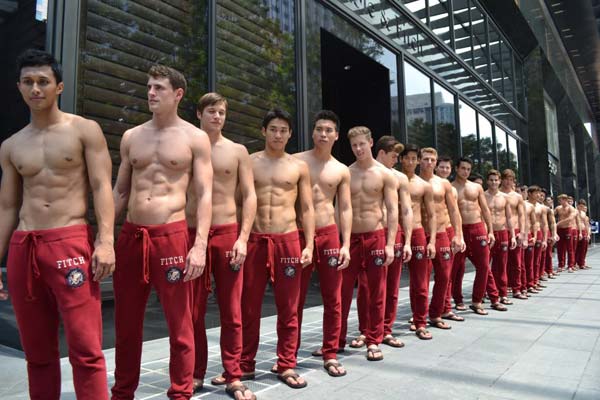 Abercrombie and Fitch staff displaying muscle in a line up outside