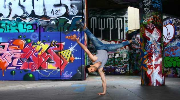 Guy showing of his athletic skills in front of grafitti